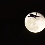 Luna in sfondo ad un aereo in volo