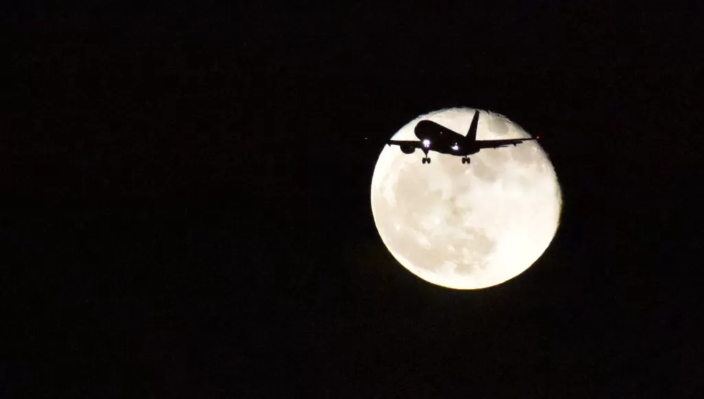 Luna in sfondo ad un aereo in volo