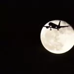 Luna in sfondo ad un aereo in volo