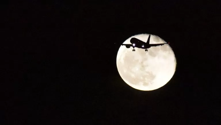 Luna in sfondo ad un aereo in volo