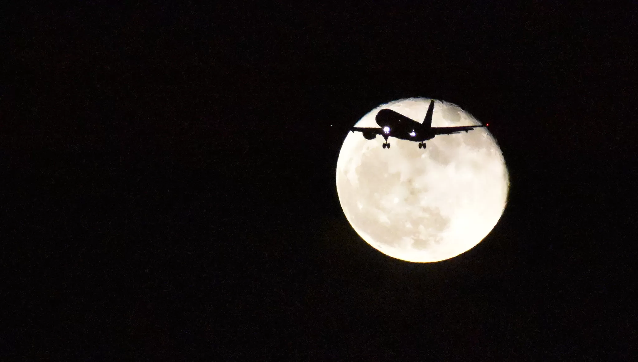 Luna in sfondo ad un aereo in volo