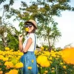 Ragazza che Annusa un Fiore in un Campo