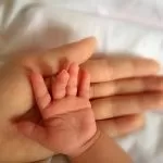 Mano di un Neonato poggiata su quella del Papà